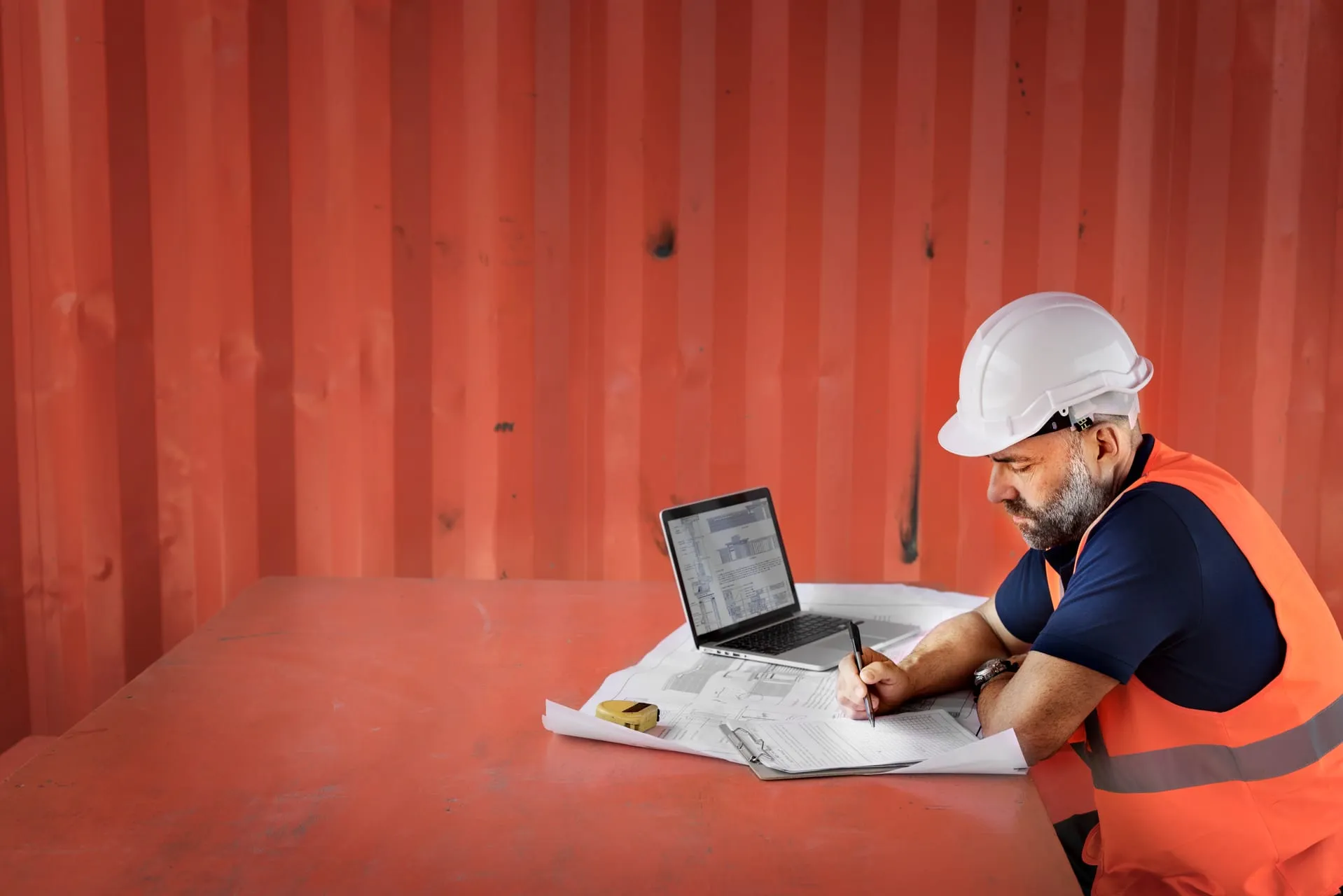 Inspector reviewing plans on site with clipboard and laptop